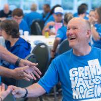 Gentleman sitting at table smiling up at someone standing by him